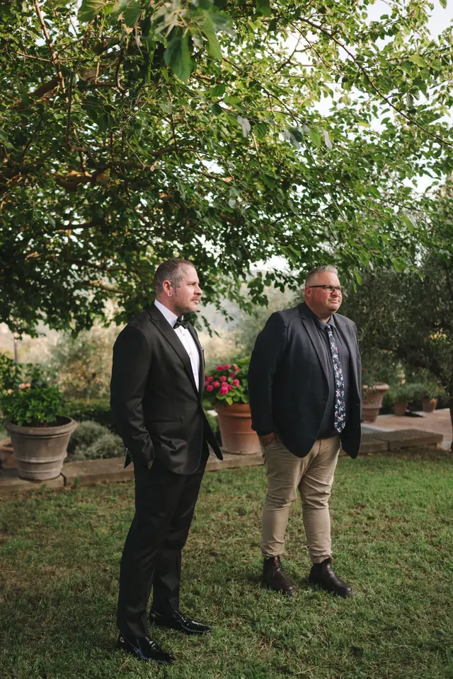 Anthony and celebrant Josh Withers wait beneath the trees before the ceremony.