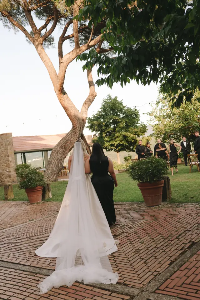 Isabella walks across the brick courtyard towards the outdoor ceremony.