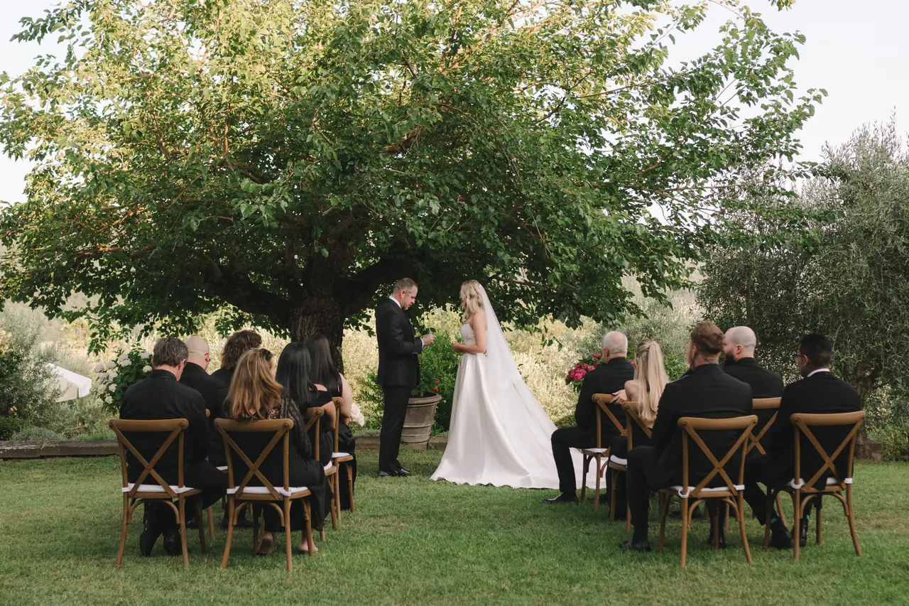 Anthony and Isabella exchange rings beneath a broad tree in the Tuscan garden.