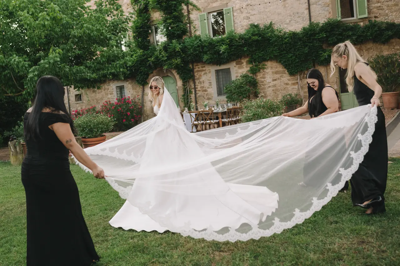 Attendants spread Isabella’s long lace veil across the garden.