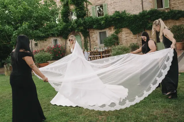 Attendants spread Isabella’s long lace veil across the garden.